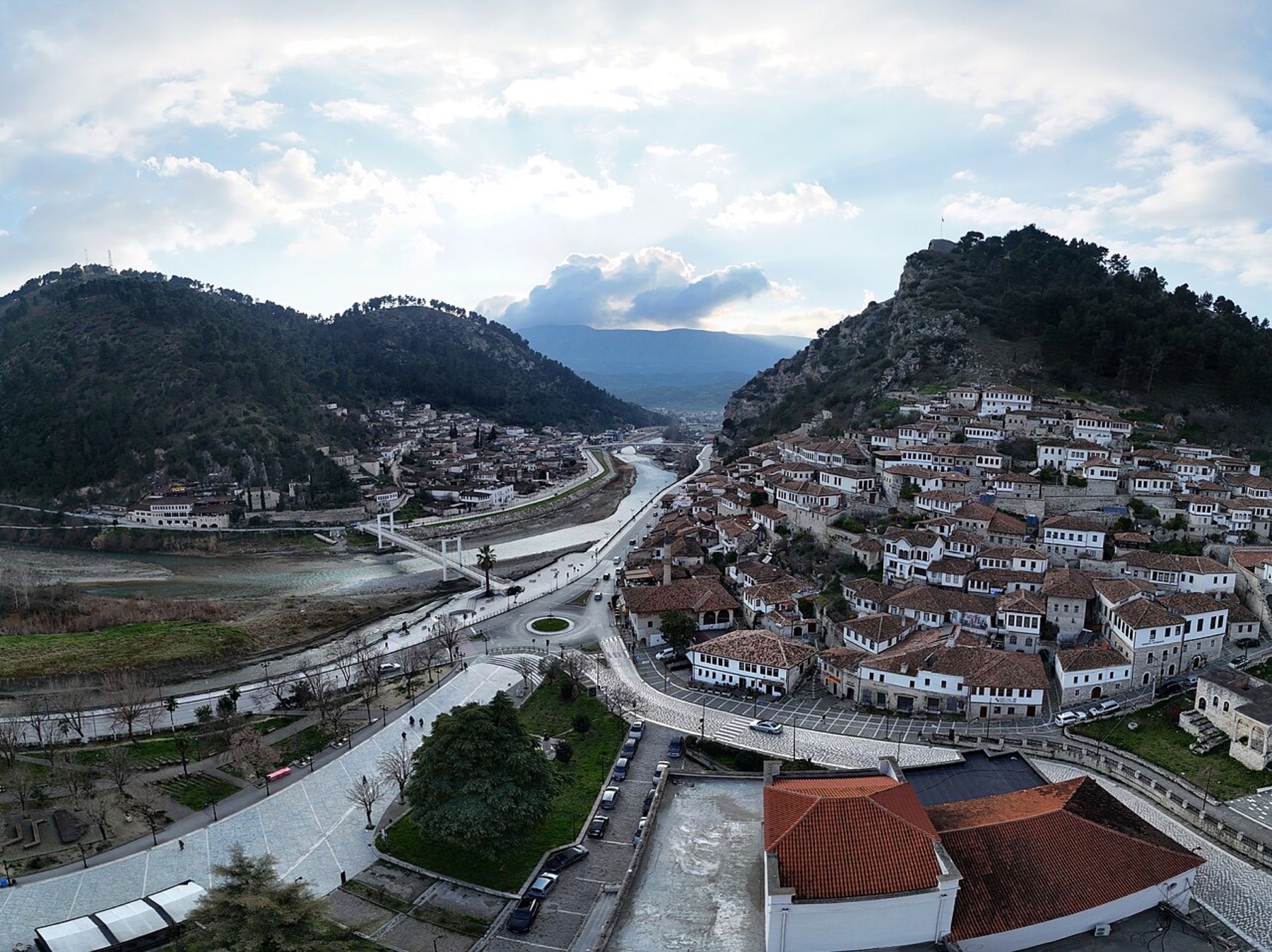White hillside houses in Berat above the Osum River and a pedestrian bridge