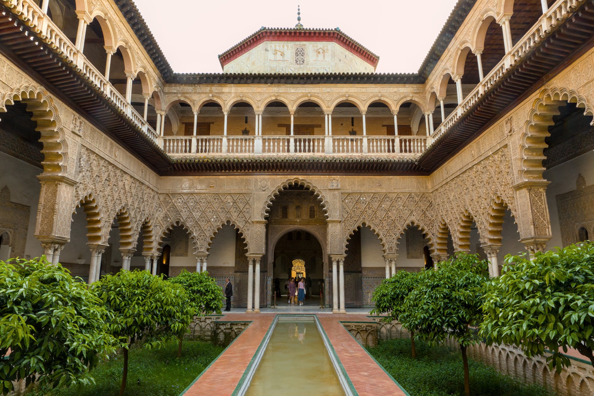 Patio de las Doncellas in the Real Alcazar of Seville: sunken garden beds, a long central pool and lobed arches with carved plasterwork