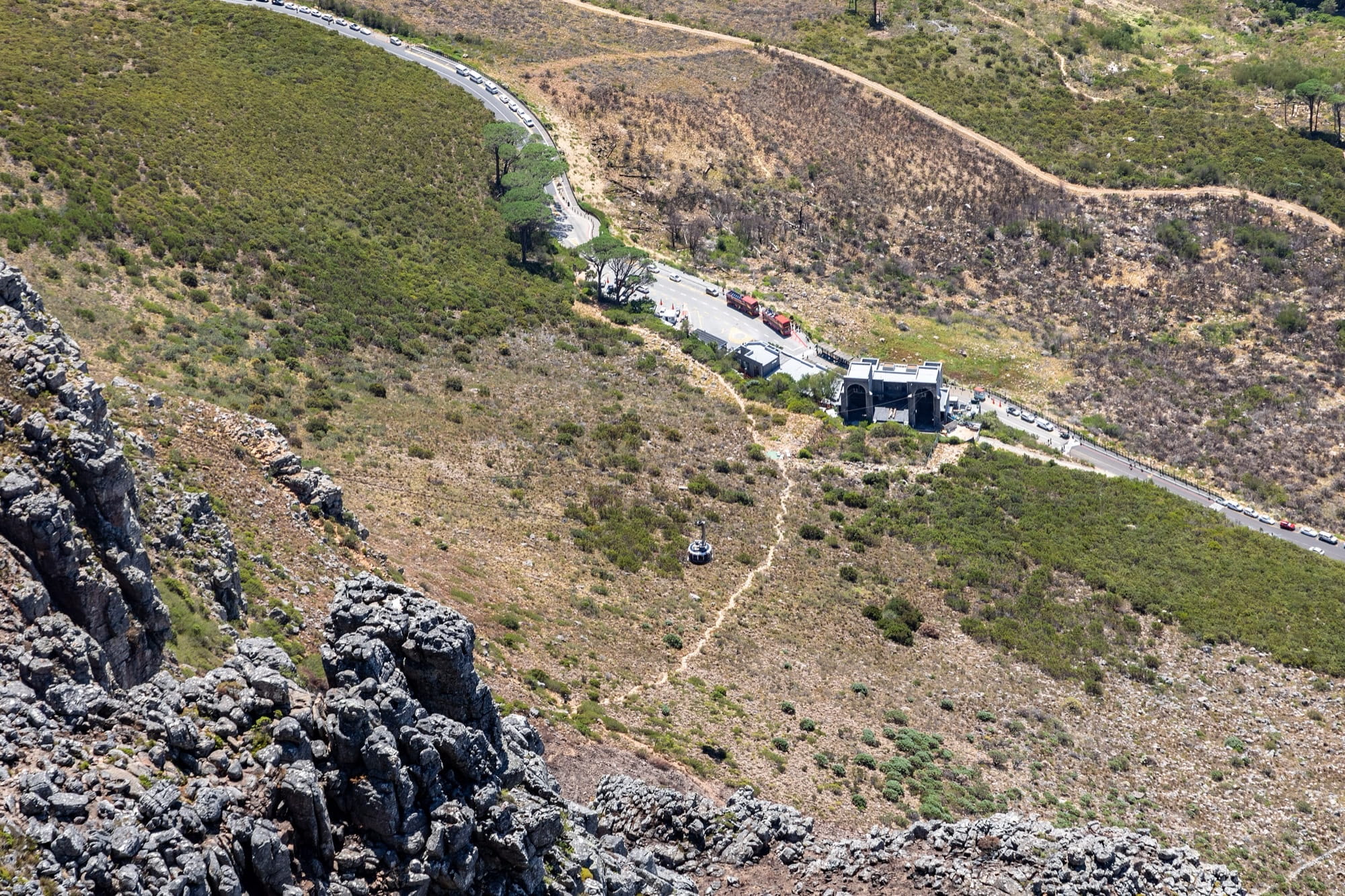 View down from Table Mountain to the Lower Cable Station, a cable car on the line, and cars parked along the curve of Tafelberg Road