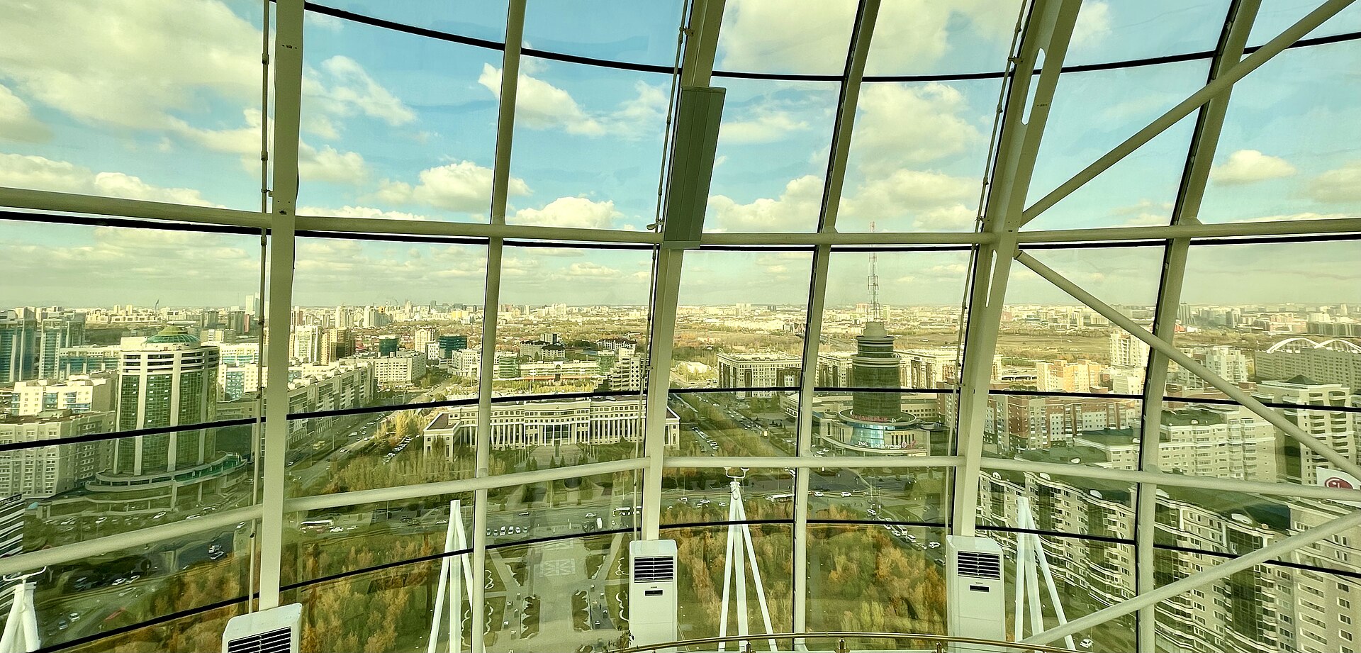 Astana streets and buildings viewed through the curved window frames of the Bayterek observation deck