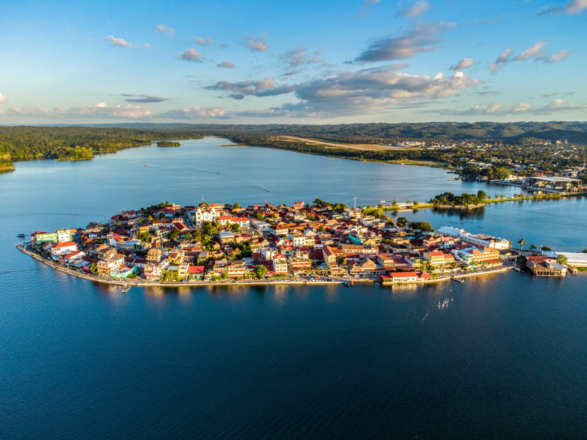Aerial view of the small island town of Flores in Lake Peten Itza with its causeway, red roofs and the mainland behind