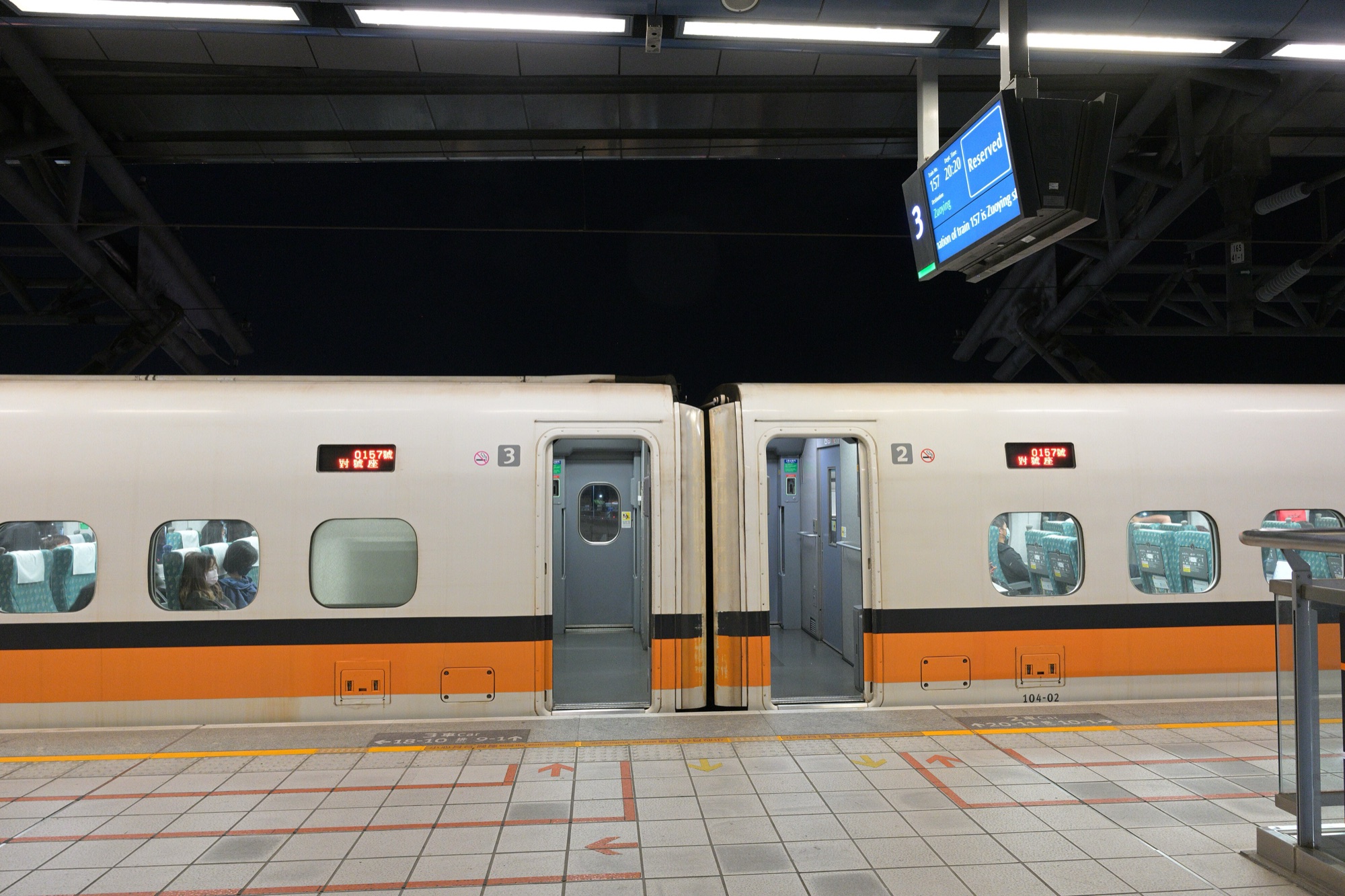 Two cars of a Taiwan High Speed Rail train with open doors at platform 3 of Taichung HSR station at night
