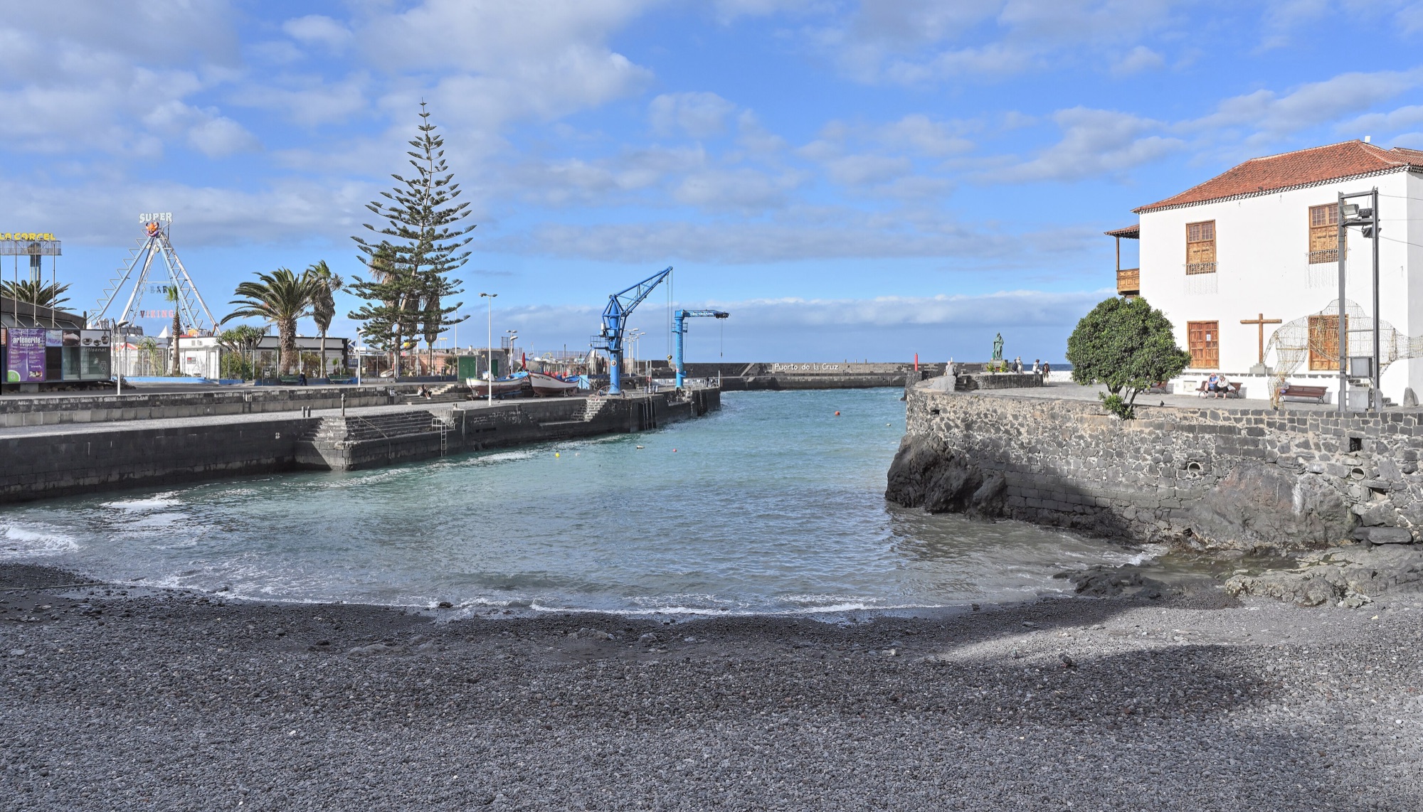 Puerto de la Cruz harbour with a black-sand beach, stone quay, the white Casa de la Aduana and palm trees