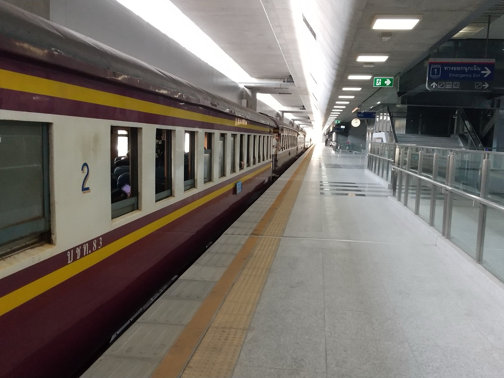 A maroon-and-cream State Railway of Thailand second-class carriage standing at a long, bright platform inside Krung Thep Aphiwat Central Terminal